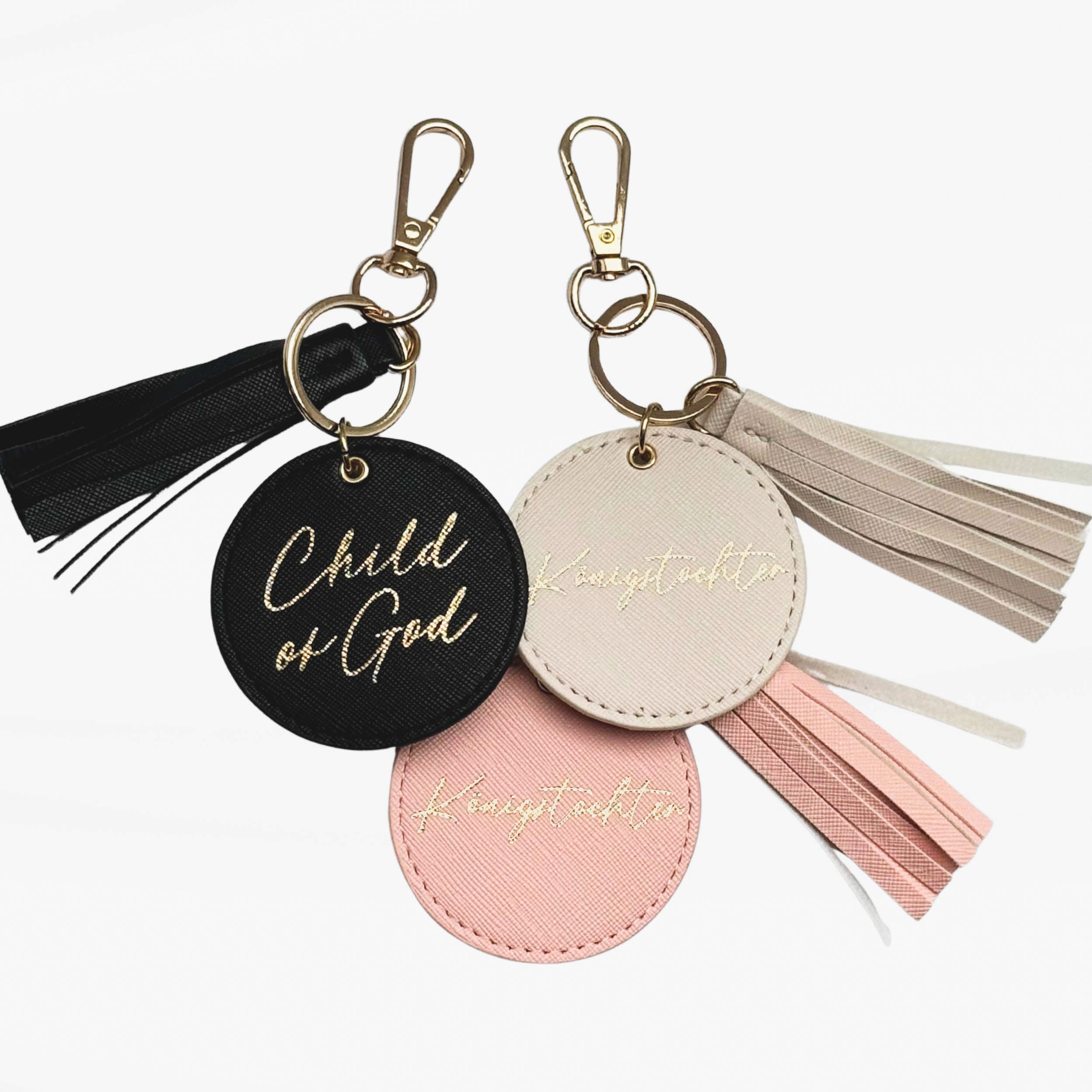 Christliche Schlüsselanhänger in beige rosa und schwarz mit goldener Aufschrift: Königstochter und Child of God.